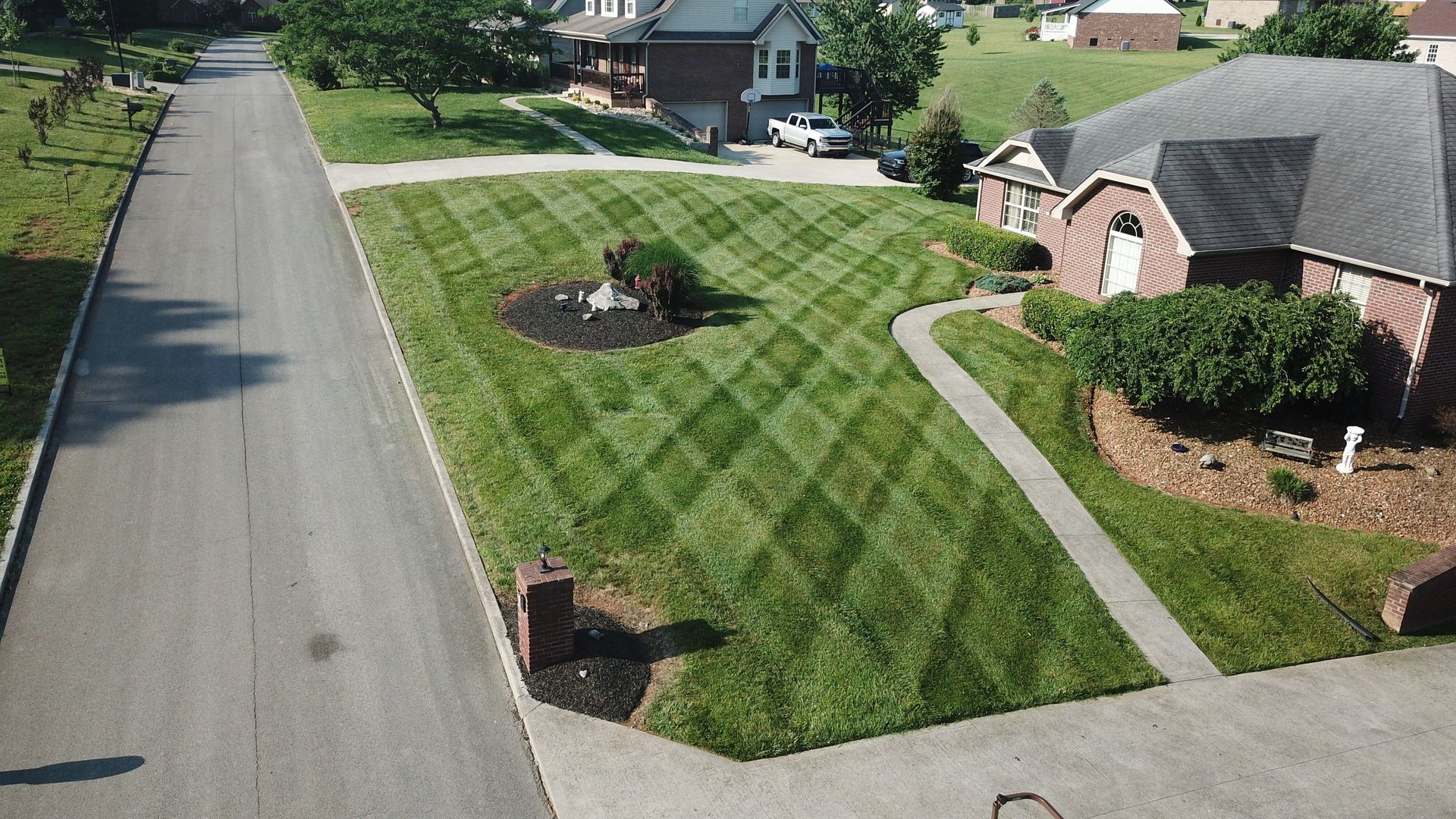 Aerial view of a residential front lawn mown in a crosshatched diamond striping pattern.