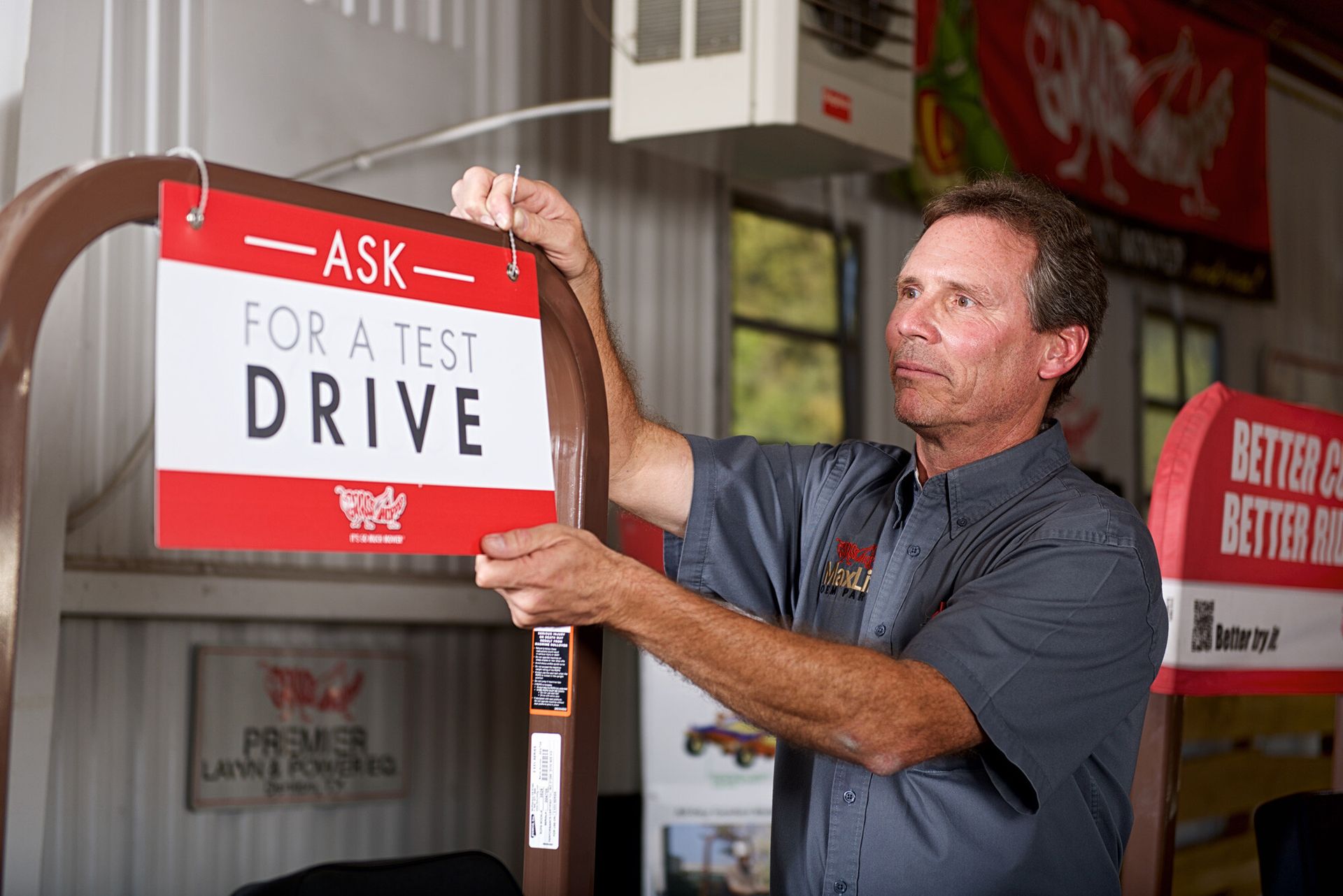 Dealership employee hanging an Ask for a Test Drive sign on a mower's rollbar.