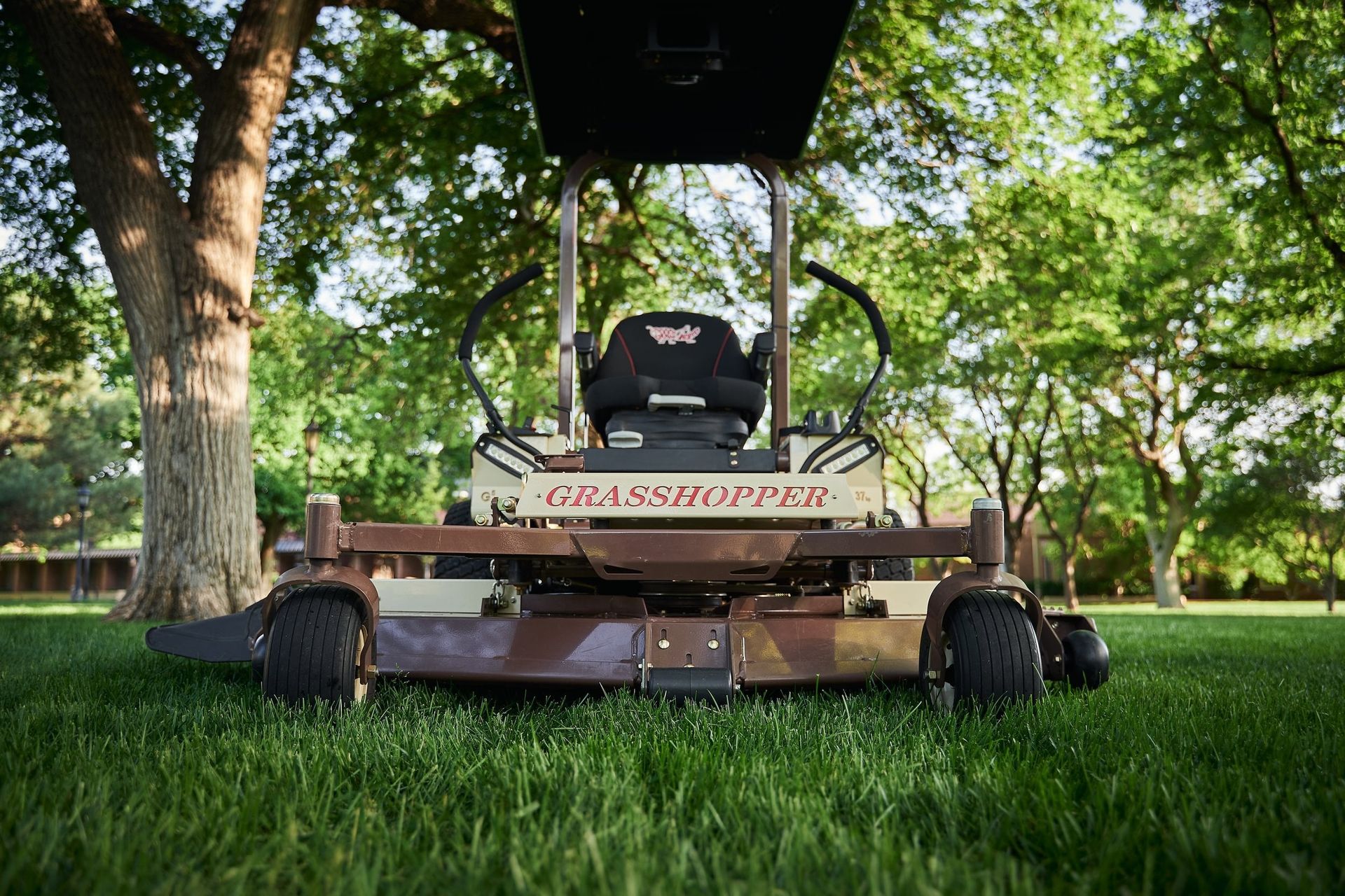 Ground-level front view of a Grasshopper cutting deck and its caster wheels on lush grass.