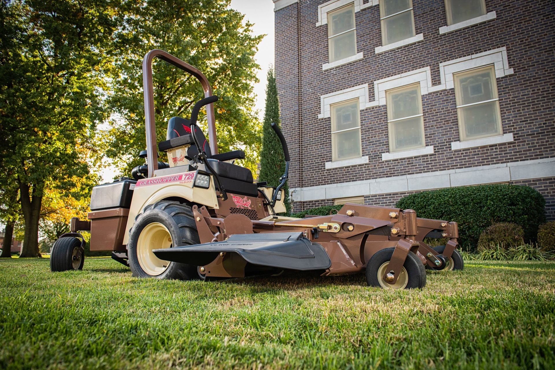 Grasshopper 729 FrontMount mower parked on turf beside a brick building with tall windows.