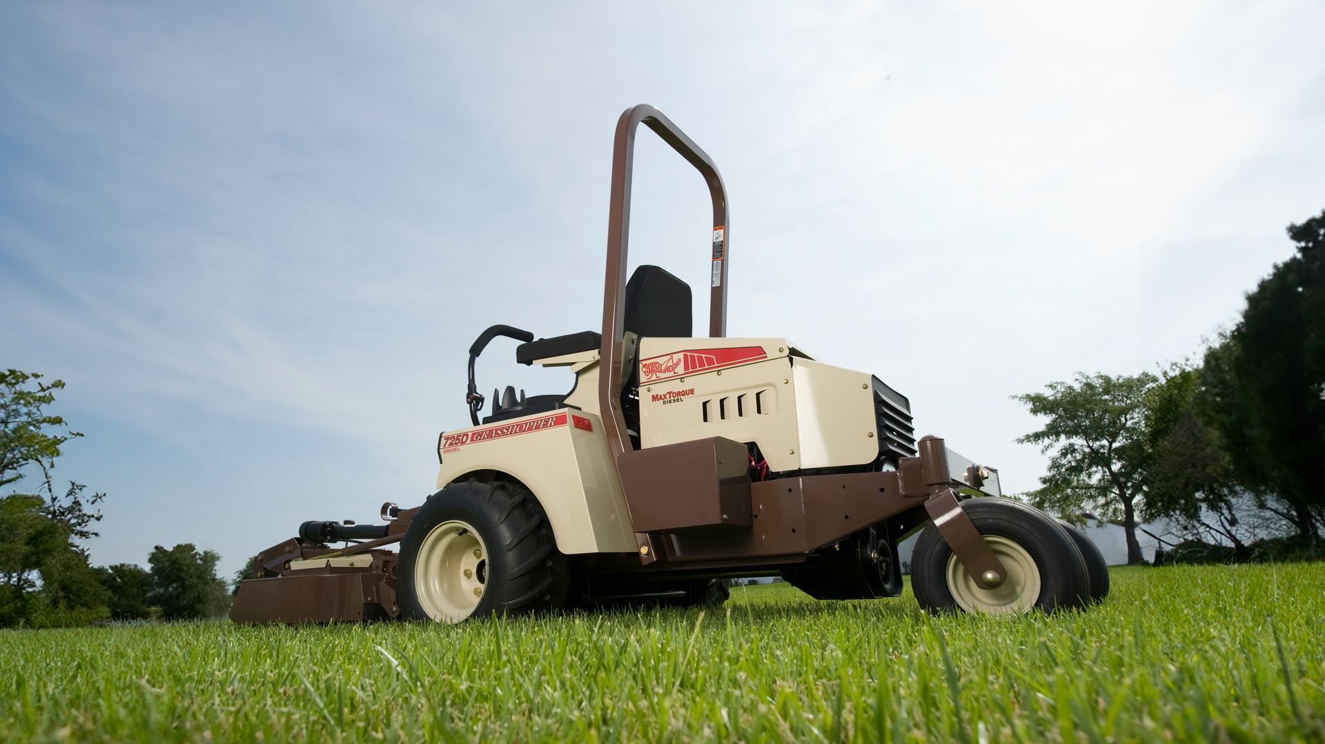 Low-angle view of a Grasshopper 725D diesel FrontMount mower on green turf under blue sky.
