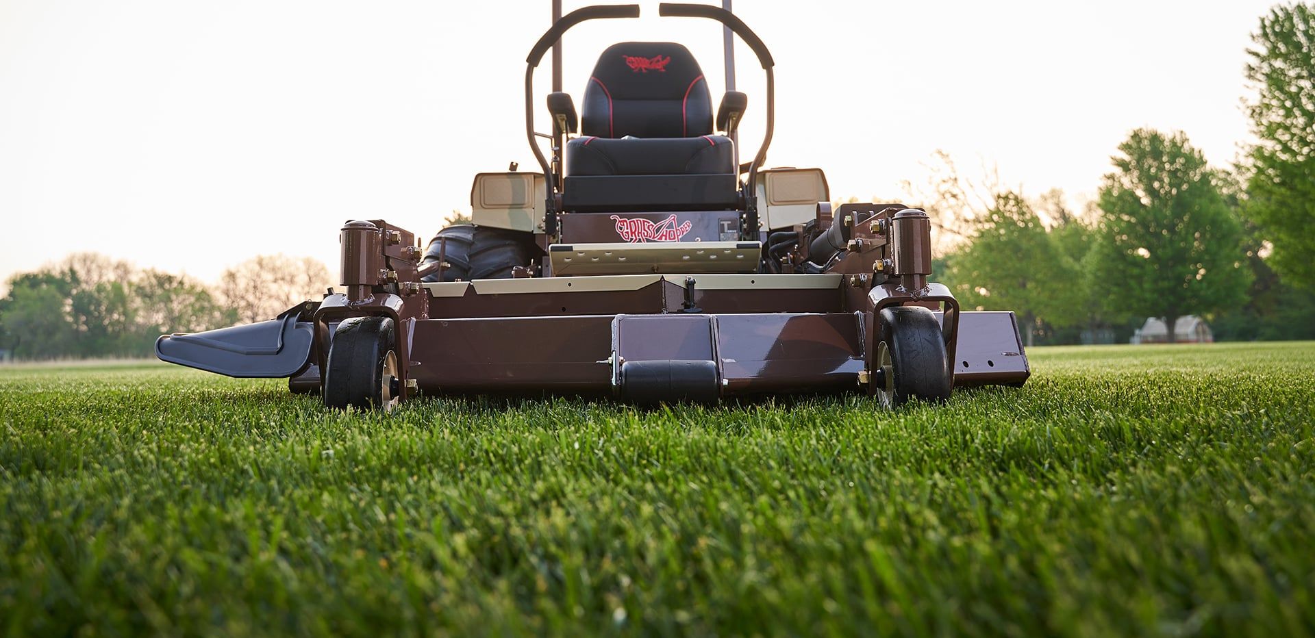 Front view of a Grasshopper FrontMount mower's wide out-front cutting deck on sunlit turf.