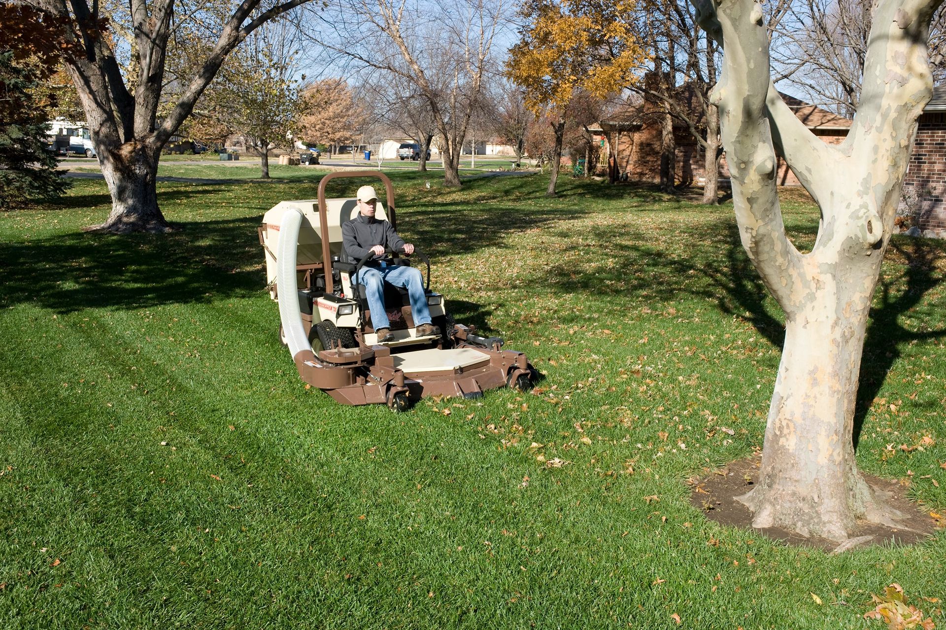 Operator collecting fallen leaves with a Grasshopper FrontMount mower and PowerVac collection system.