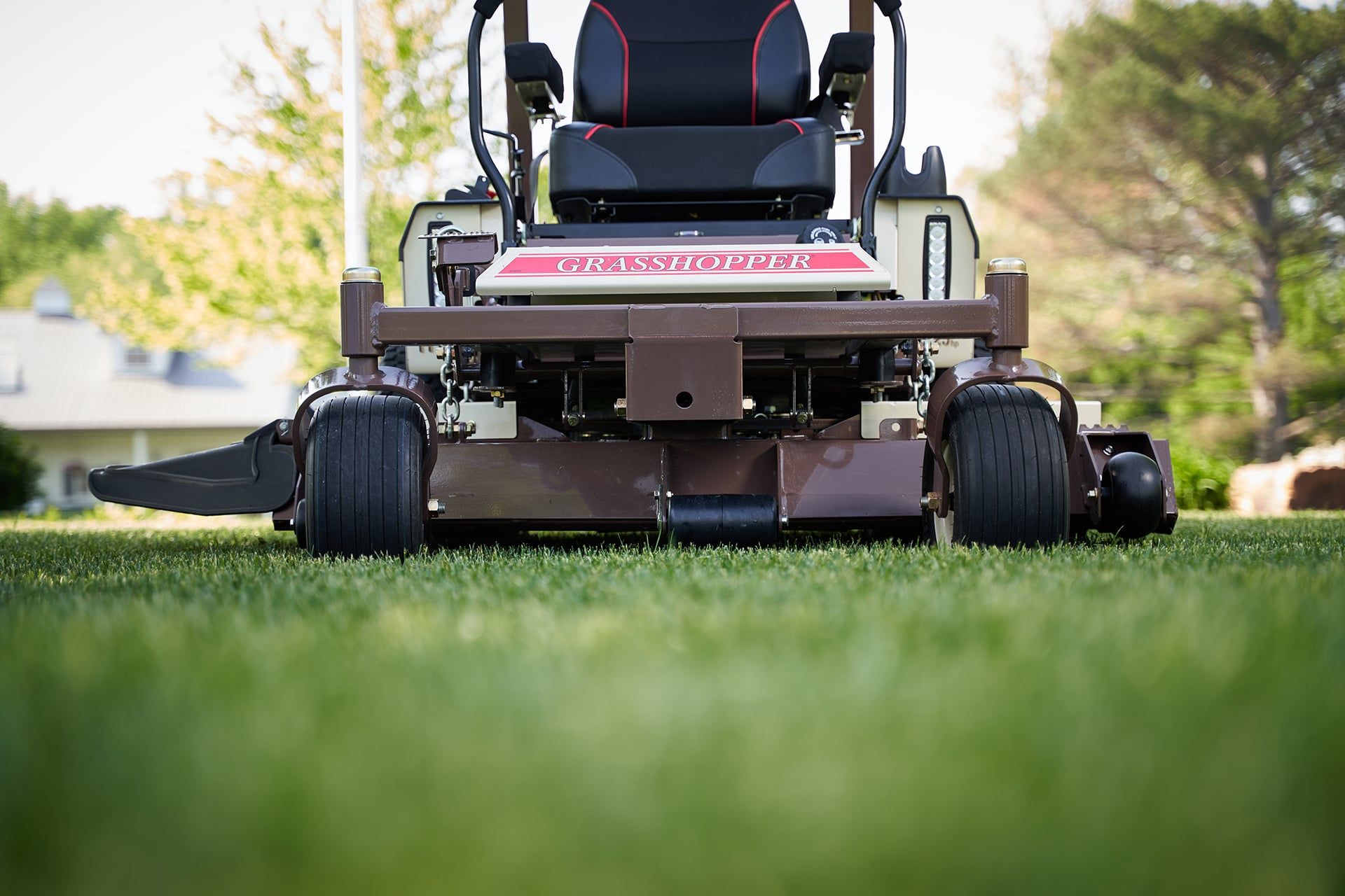 Front view of a Grasshopper MidMount mower's cutting deck, caster wheels, and side-discharge chute.