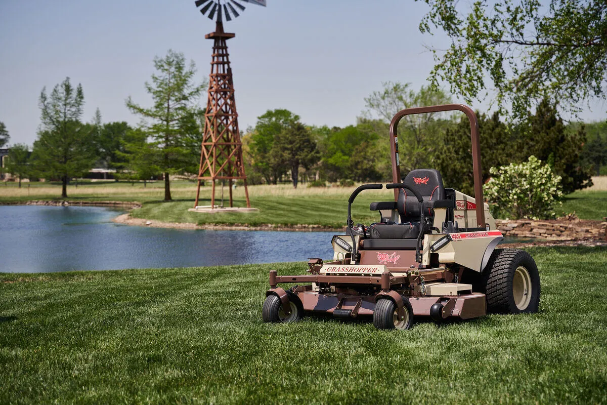 Grasshopper 400D FrontMount mower parked on mown turf beside a pond and windmill tower.