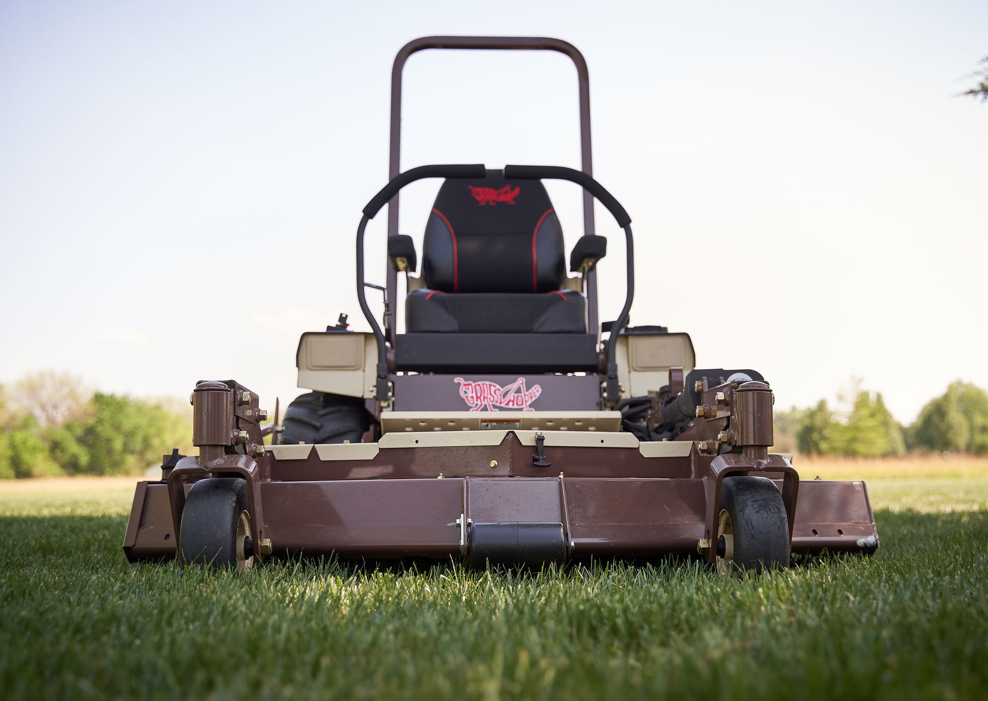 Grasshopper FrontMount zero-turn mower parked head-on in lush green grass with its wide deck lowered.