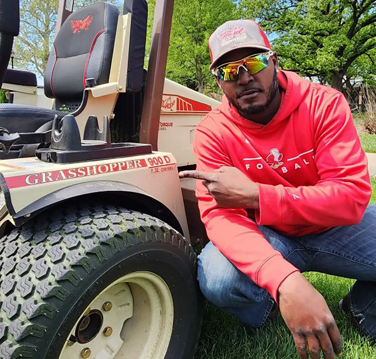 Man in a red hoodie pointing at the Grasshopper 900D diesel decal on a fender.